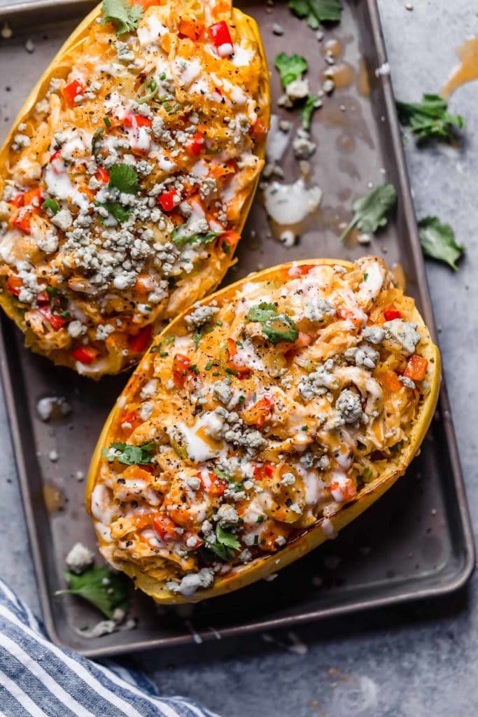 Overhead view spaghetti squash halves filled with buffalo chicken, topped with ranch dressing.