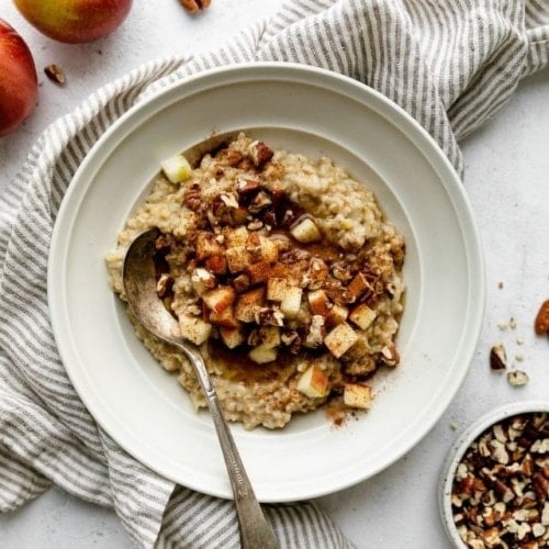 Instant Pot Apple Cinnamon Oatmeal in a white bowl topped with apples, pecans, and cinnamon.