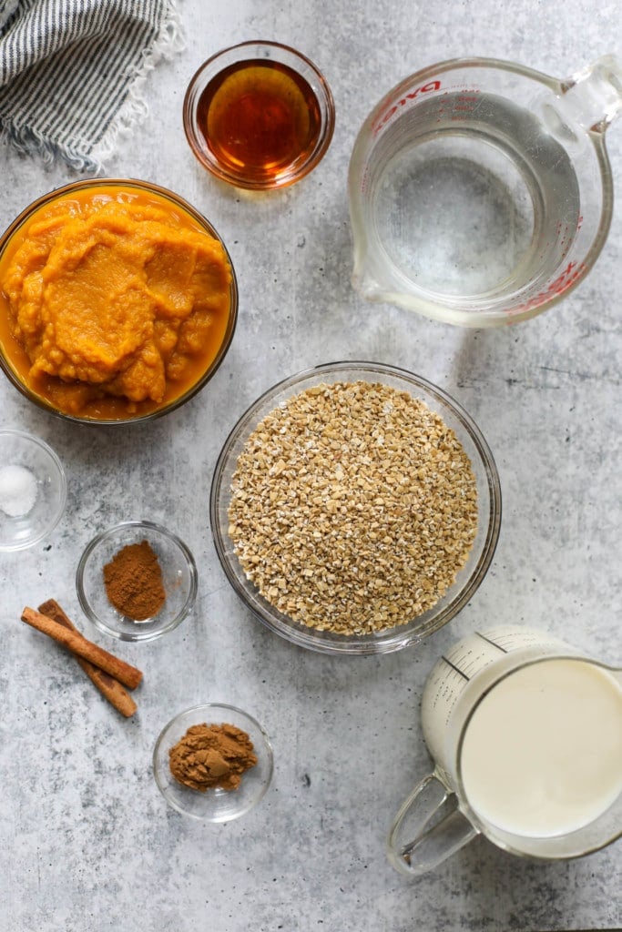 All ingredients for Instant Pot Pumpkin Oatmeal in small bowls and measuring cups arranged together.