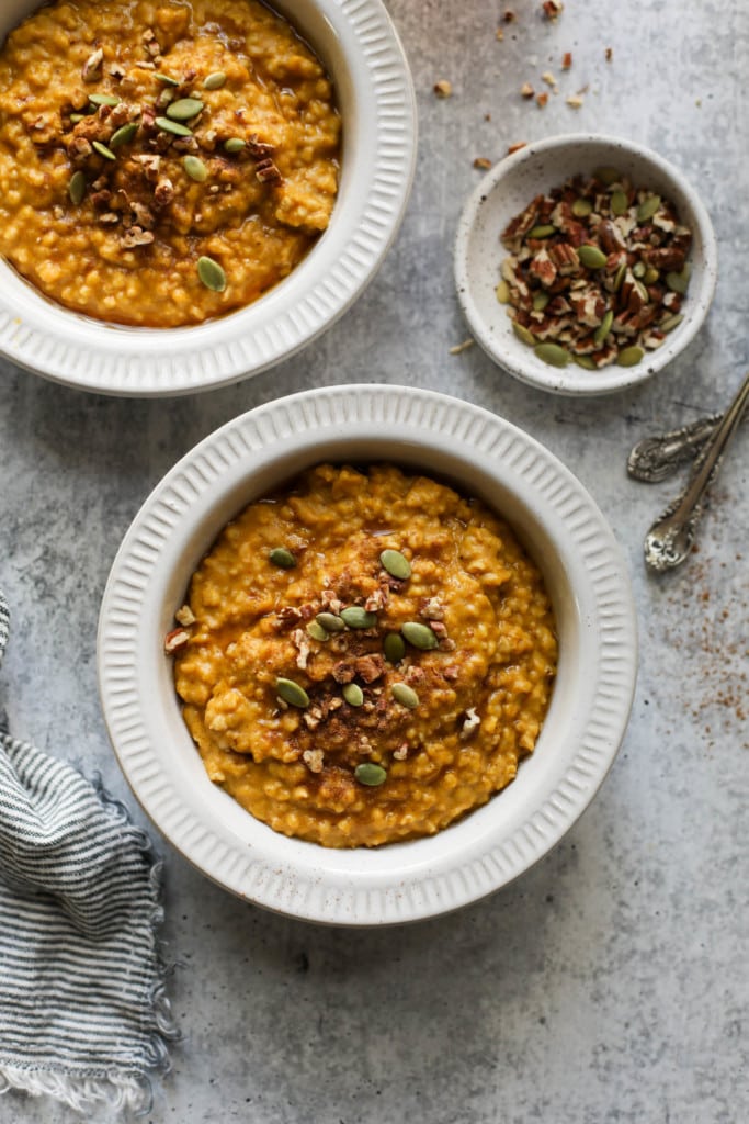 Instant Pot Pumpkin Oatmeal served in white bowls topped with pepitas and cinnamon.