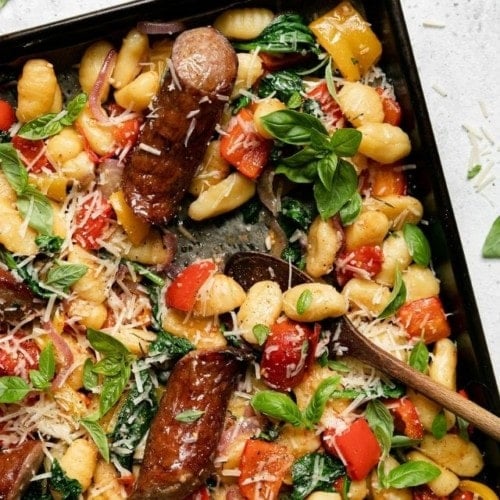Gnocchi, kielbasa, vegetables, and fresh herbs baked on a sheet pan sprinkled with fresh parmesan.