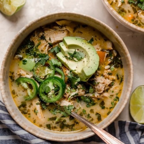 Slow Cooker White Chicken Chili in a bowl topped with jalapeno and avocado slices.