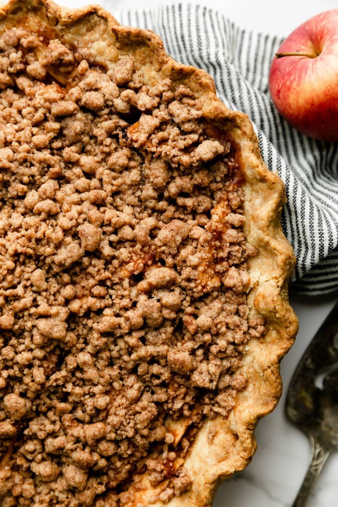 Close up view of apple pie with fluted edge pie crust and crumb topping.