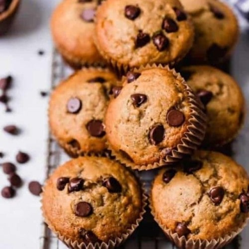 A pile of gluten-free banana muffins with chocolate chips on a cooling rack.