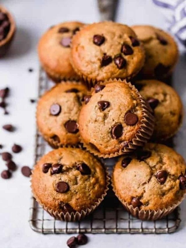 A pile of gluten-free banana muffins with chocolate chips on a cooling rack.