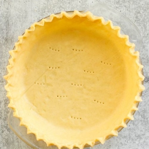 Overhead view of a gluten-free pie crust with fluted edges in a glass pie plate.