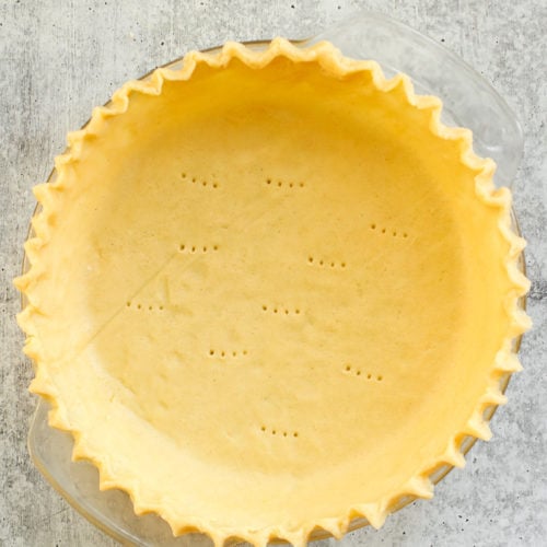 Overhead view of a gluten-free pie crust in a pie plate with fluted edges.