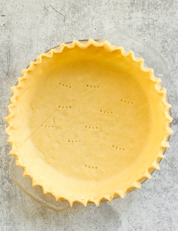 Overhead view of a gluten-free pie crust in a pie plate with fluted edges.