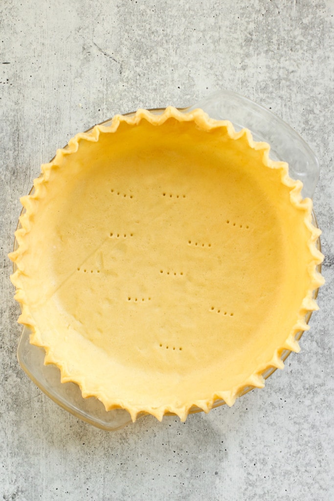 Overhead view of gluten-free pie crust in a pie plate with fluted edges.