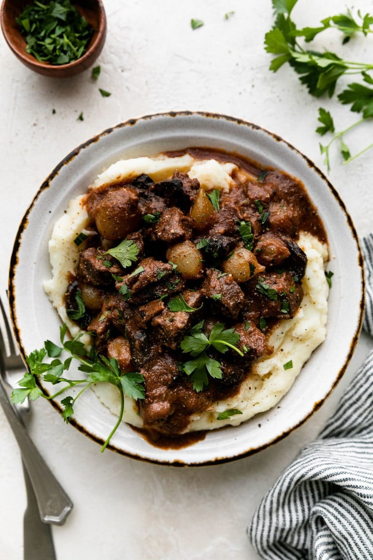 Crockpot beef tips with gravy served over mashed potatoes.