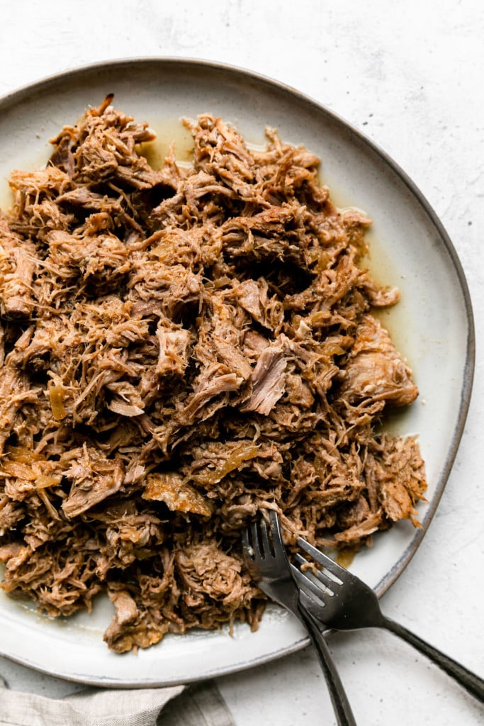 Shredded pork on a serving platter with a fork in the meat.