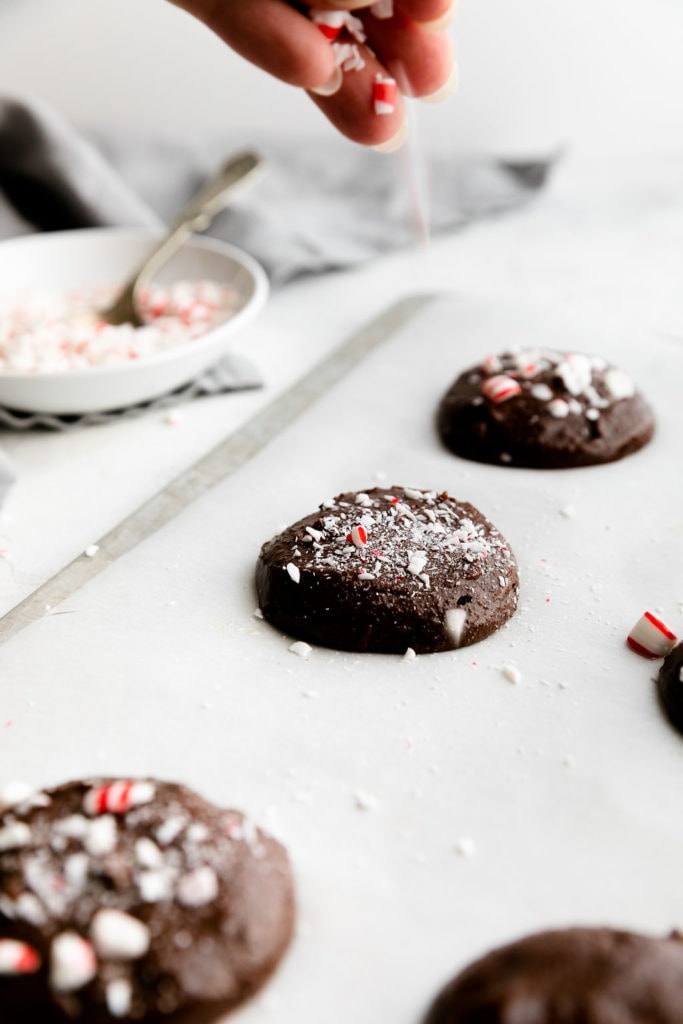 Brownie cookies with peppermint candy cane pieces sprinkled on top on a baking sheet