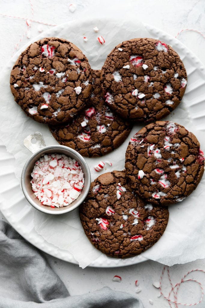 Peppermint brownie cookies on a white serving tray with extra peppermint pieces scattered around.