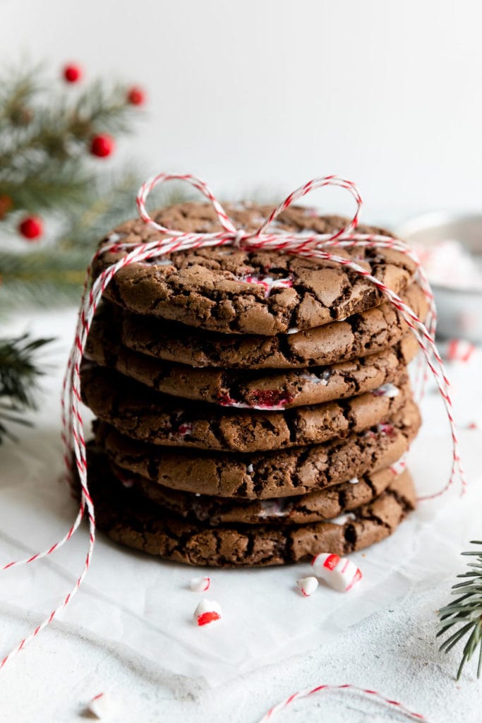 A stack of brownie cookies with peppermint candy pieces melted in tied together with a red and white string.