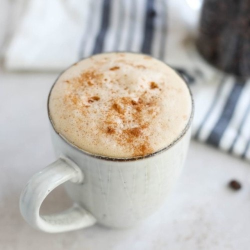 A mug filled with cinnamon coconut latte topped with froth and cinnamon