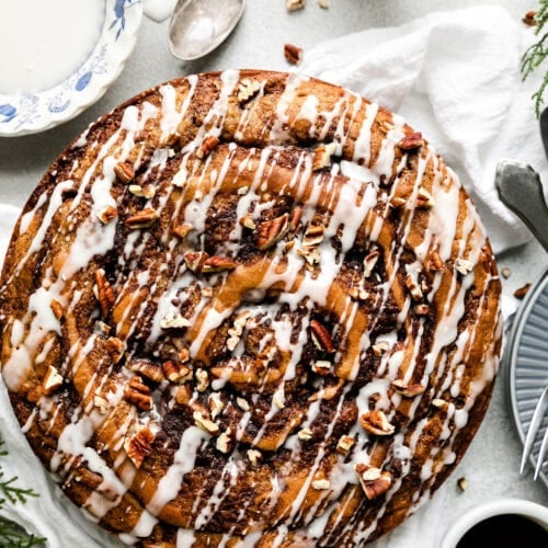 Overhead view round cinnamon roll coffee cake with white glaze drizzled over top.