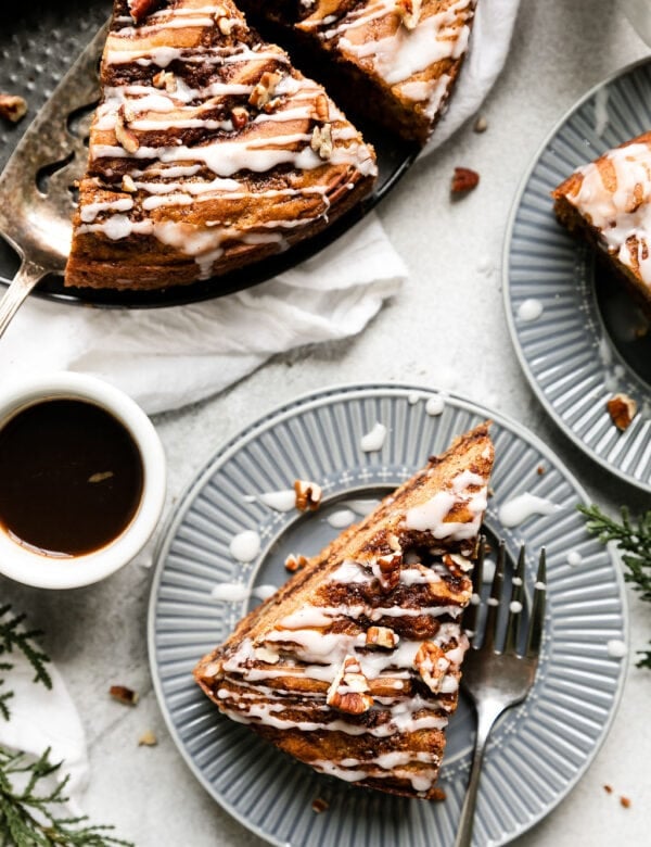Overhead view several slices of cinnamon roll coffee cake plated on blue plates
