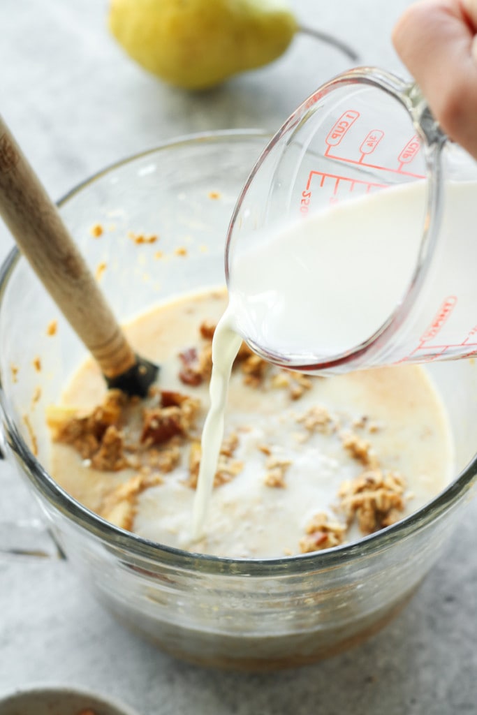 Milk being poured into a mixing bowl of ingredients for gingerbread baked oatmeal