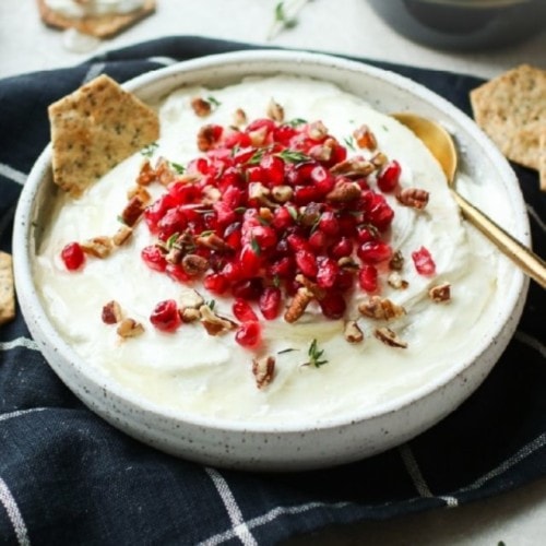 Honey whipped goat cheese in a shallow bowl topped with pomegranates and pecans.