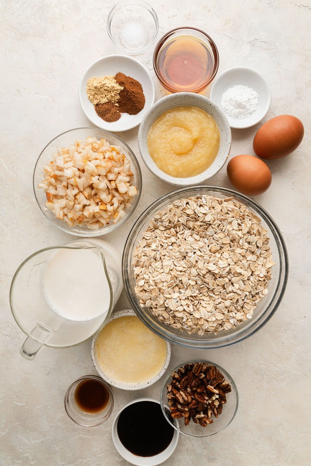 Overhead view of a variety of ingredients for Gingerbread Baked Oatmeal in different sized bowls.
