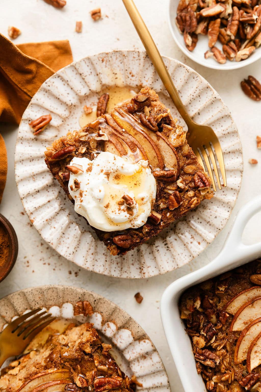 Overhead view of a plate with a piece of Gingerbread Baked Oatmeal on it topped with a dollop of yogurt and drizzled with syrup.