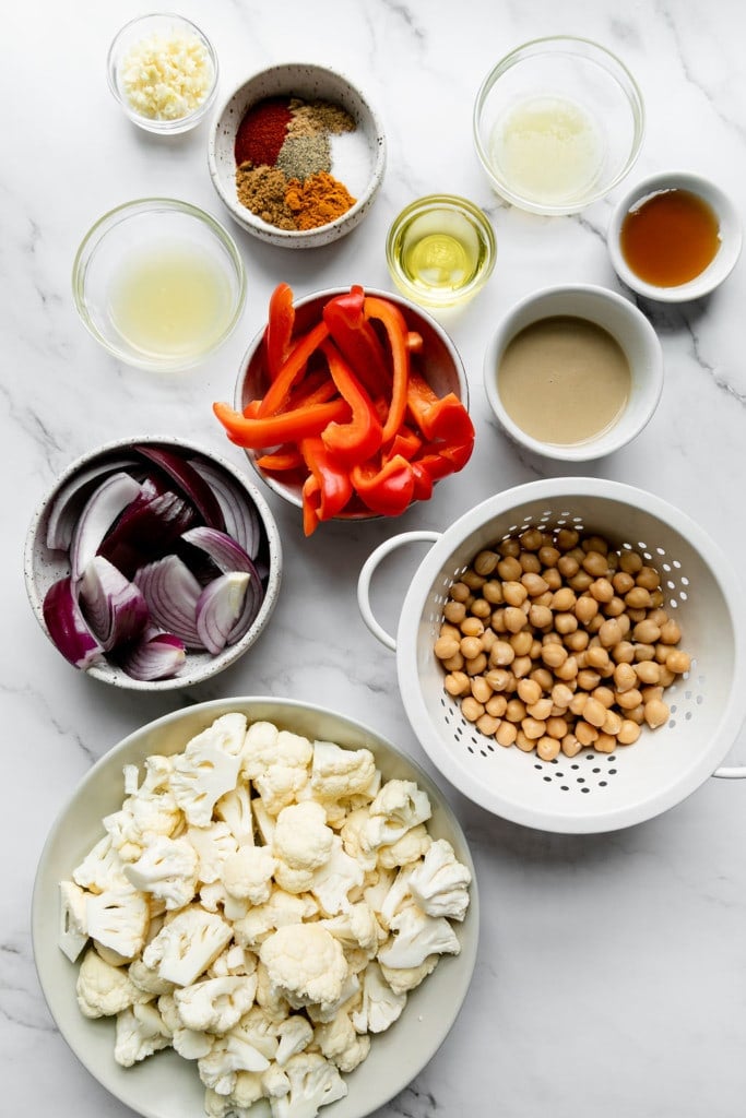 All ingredients for sheet pan veggie shawarma arranged together in small bowls and a colander. 