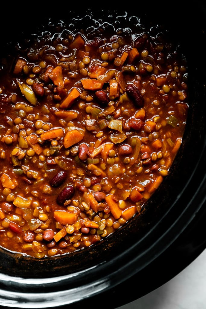 Overhead view of lentil chili in a black slow cooker