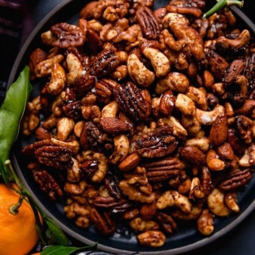 Overhead view of slow cooker spiced nuts in a black bowl