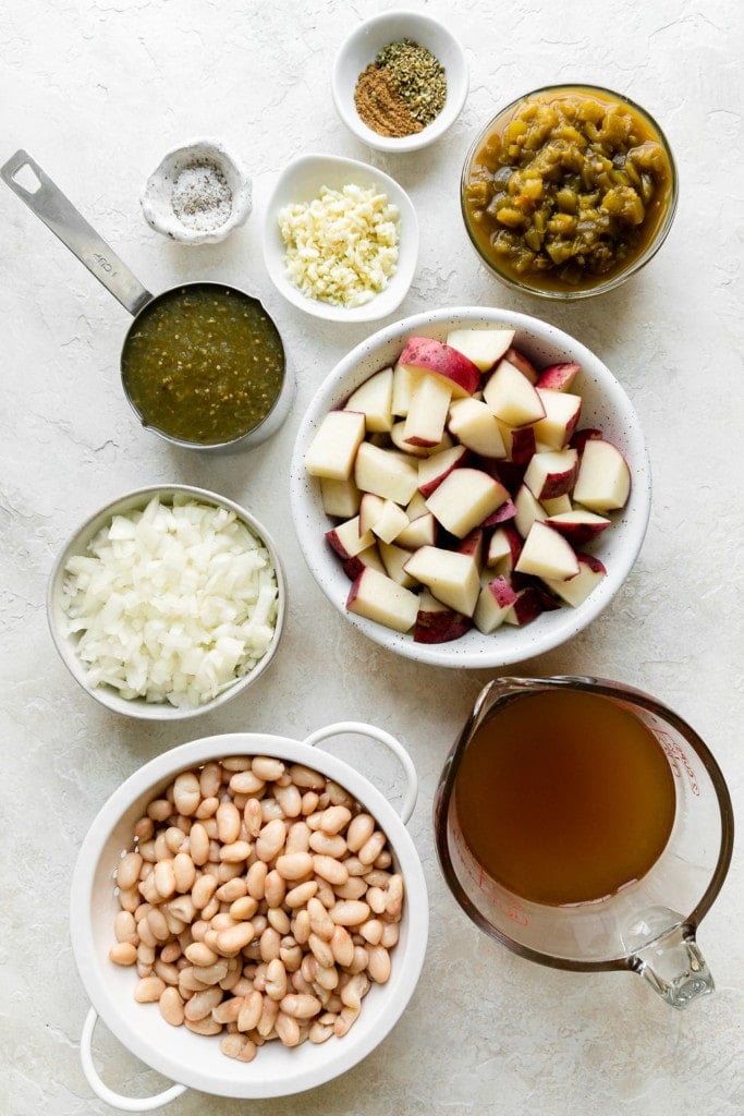 All ingredients for slow cooker vegan green chili stew arranged together in bowls and measuring cups.