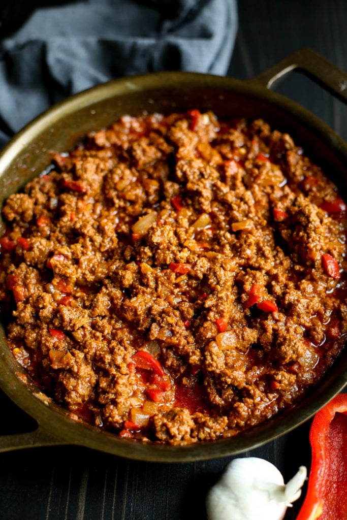 Stovetop Sloppy Joes in a skillet, diced red peppers and onions mixed in.