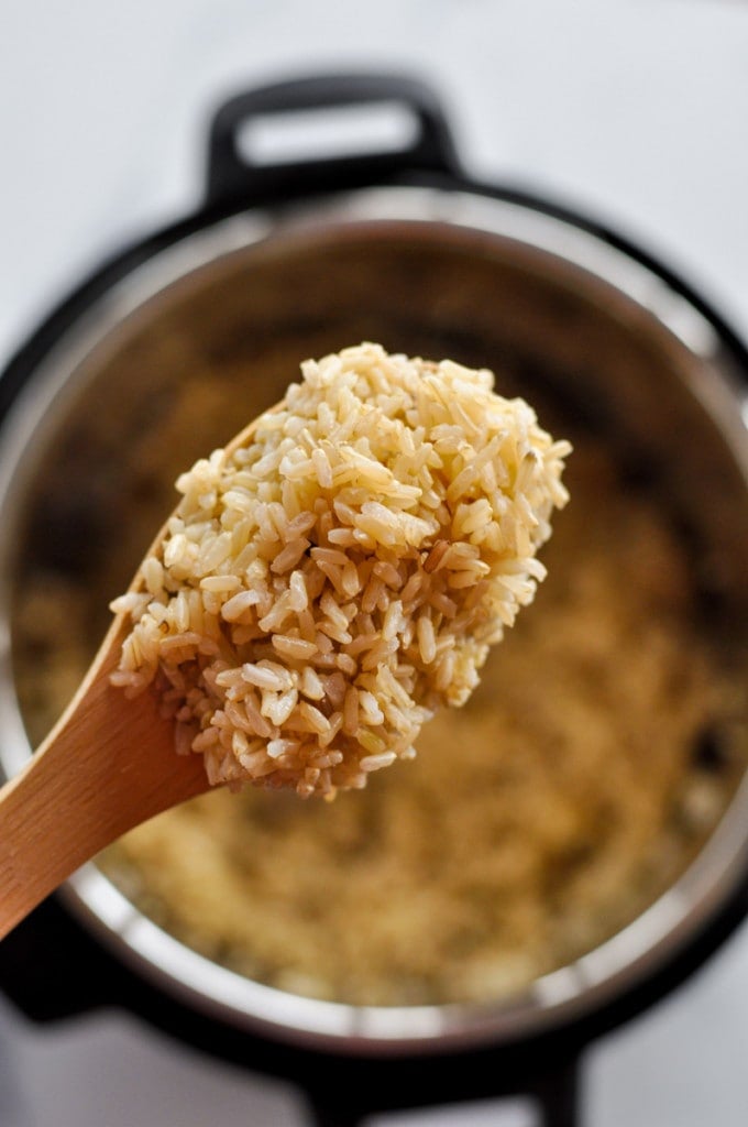 Instant Pot Brown Rice serving on a wooden spoon over an Instant Pot.