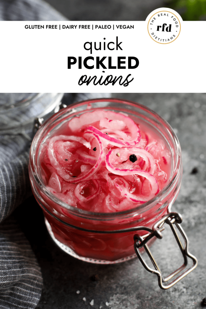 Quick pickled red onions in a mason jar in vinegar with peppercorns on top.