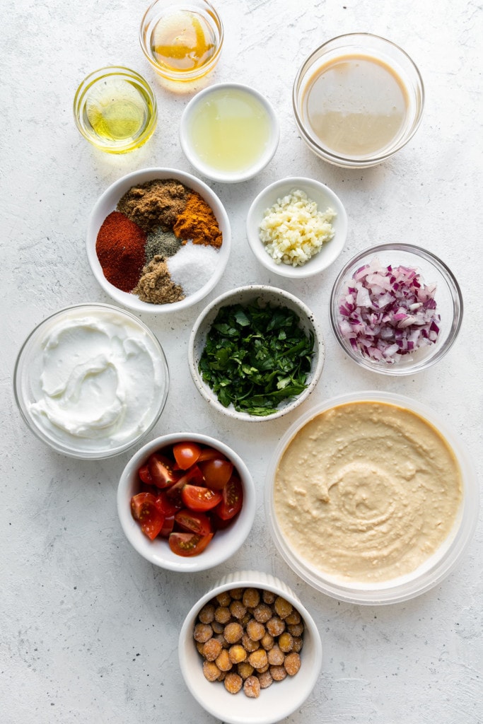 All ingredients for layered Shawarma dip arranged together in small bowls.