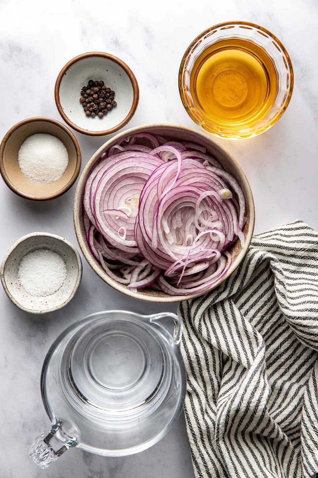 Overhead view of a variety of ingredients for Quick Pickled Onions in different sized bowls. 