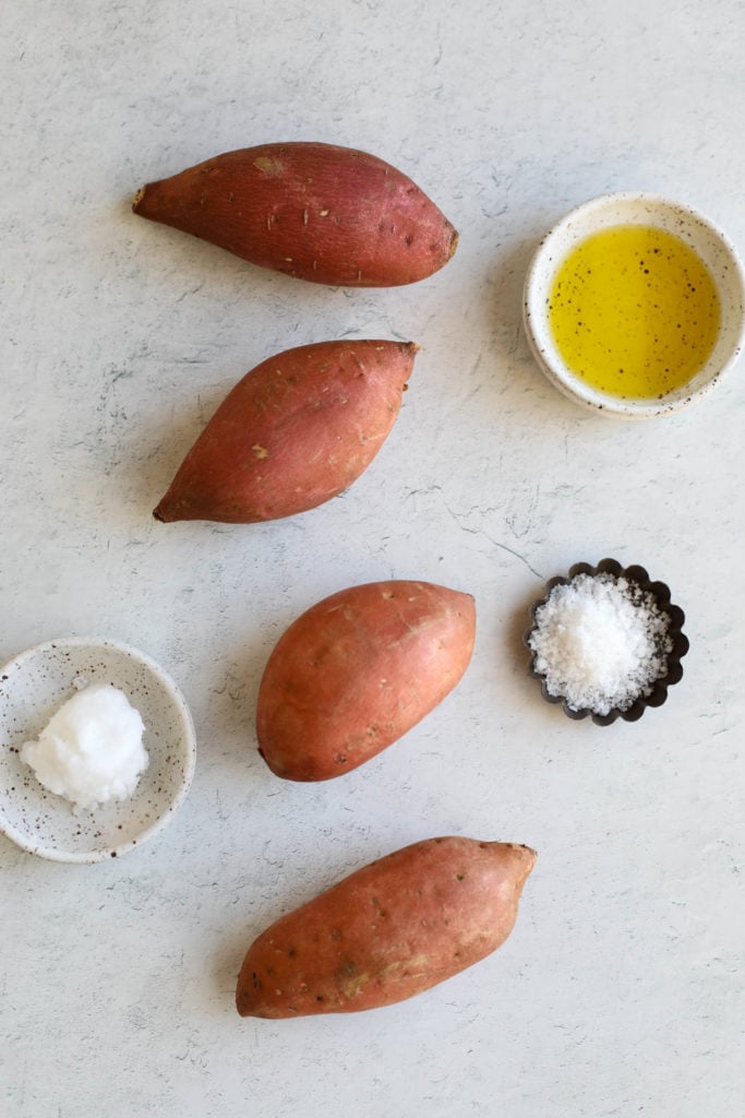 All ingredients for oven baked sweet potatoes arranged together on a cement countertop.