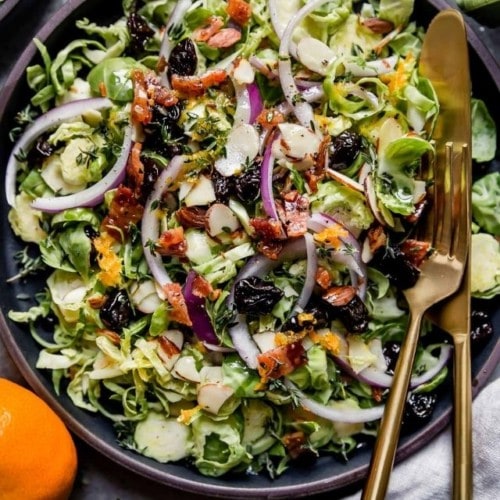 Overhead view of shaved Brussels sprouts salad with citrus vinaigrette tossed together in a black serving bowl.