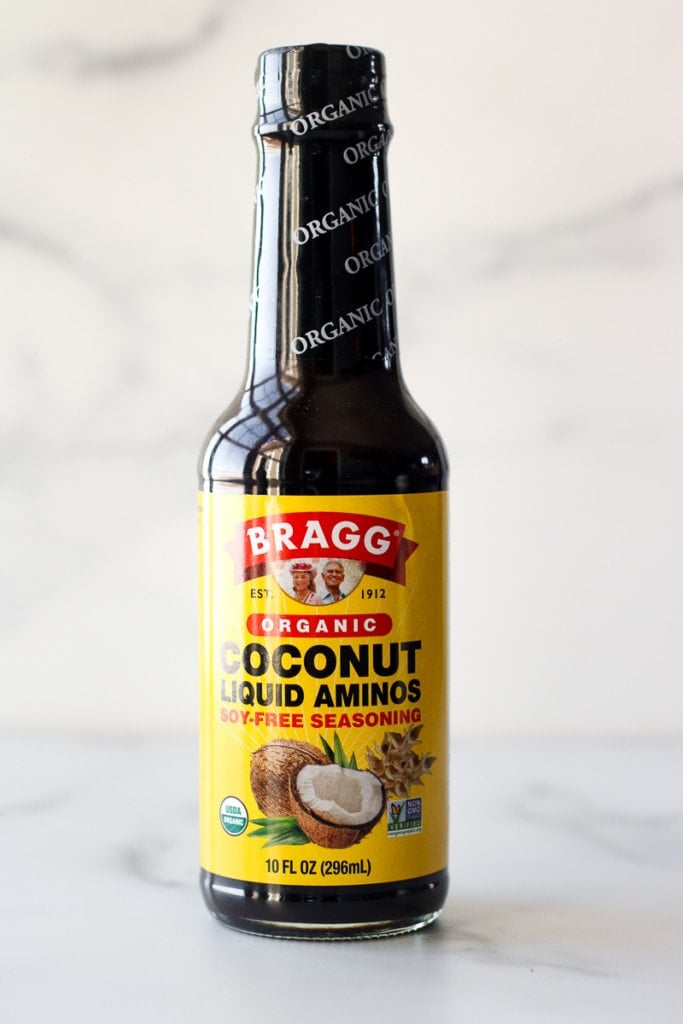 A glass bottle of Bragg coconut aminos.
