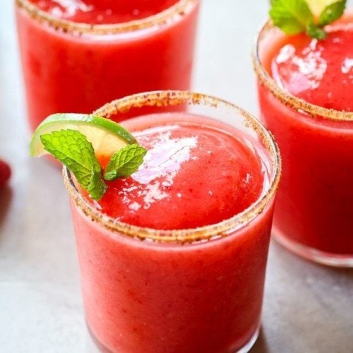 Three glasses of frozen strawberry margaritas in short clear glasses.