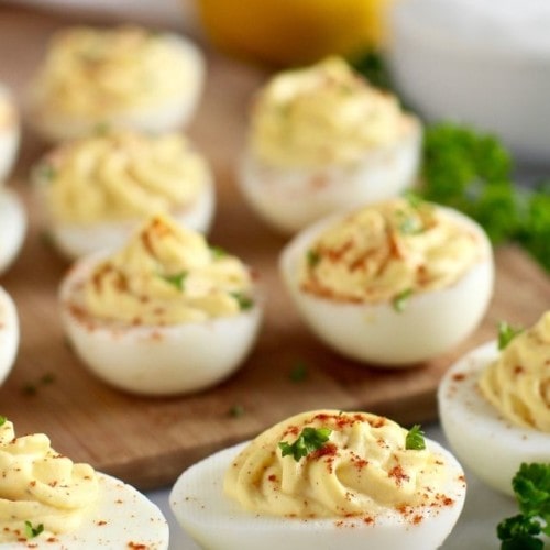 Greek yogurt deviled eggs filled with creamy swirled filling, topped with paprika and fresh herbs.