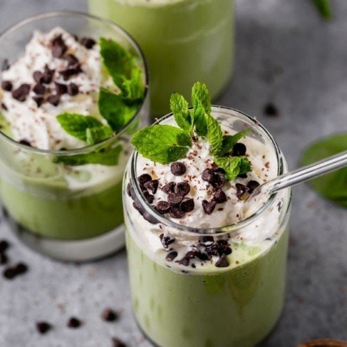 Mint Chocolate Chip Milkshake in tall clear glasses topped with whipped cream.