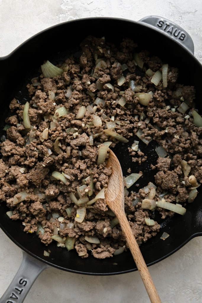 Overhead view of browned ground beef with onions in a skillet.