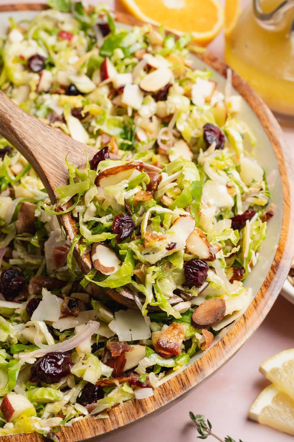 A wooden spoon lifting a scoop of shaved Brussels sprouts salad from a bowl.