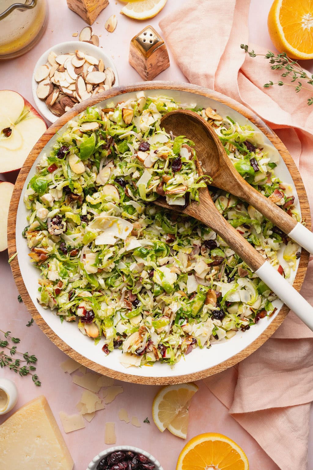 A bowl of shaved Brussel sprouts salad with two serving spoons on top.