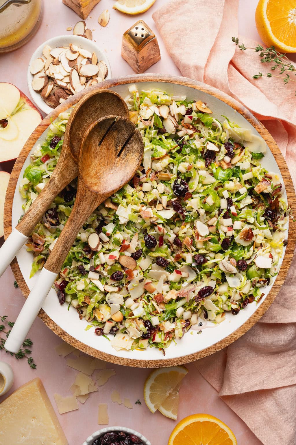 A shaved Brussels sprouts salad in a bowl with two wooden serving spoons on top.