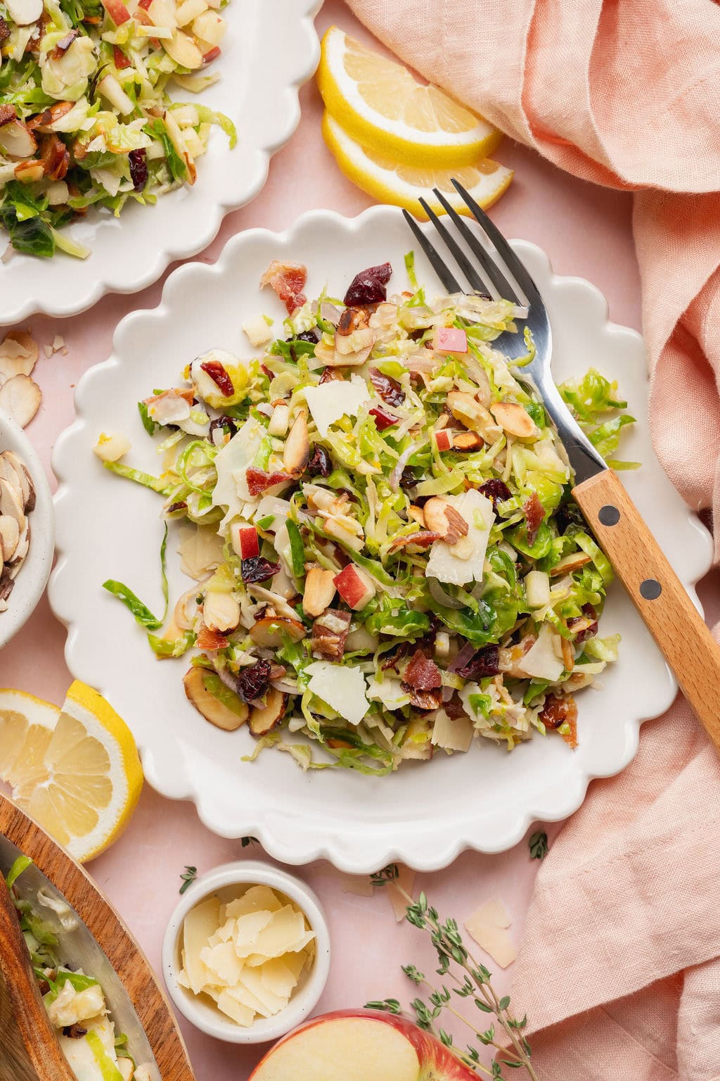 A serving of shaved Brussels sprouts salad on a white plate with a fork on the side.