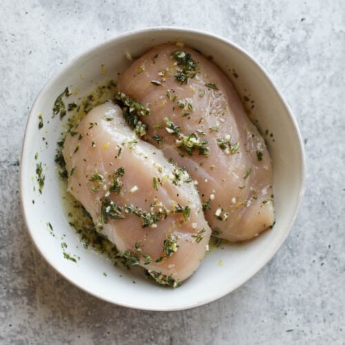 Overhead view of lemon herb chicken breasts marinating.