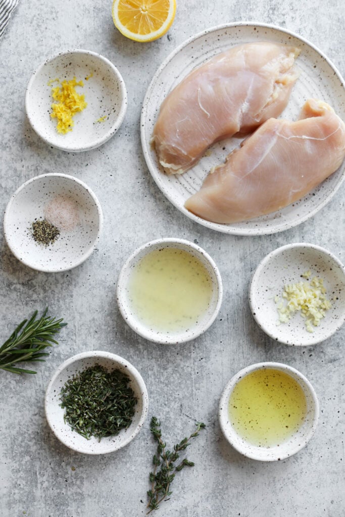 Overhead view of all ingredients for lemon chicken marinade arranged in small bowls and a plate. 