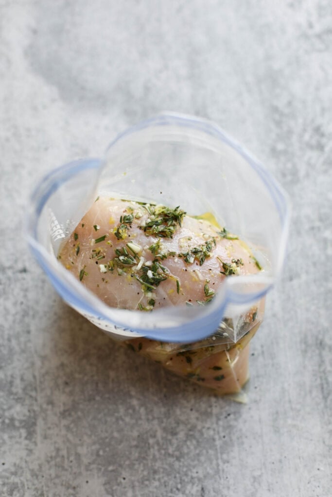 Overhead view looking down into a ziplock bag filled with chicken breasts marinating in lemon chicken marinade.