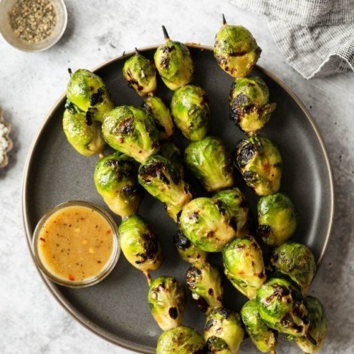 Overhead view of Grilled Brussels Sprouts with maple-mustard glaze on a grey plate.