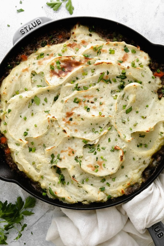 Overhead view of lentil shepherd's pie in a cast iron skillet with creamy baked mashed potatoes on top.